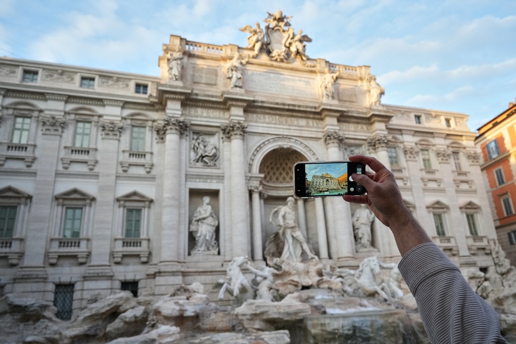 A visitor takes a photo of Rome's Trevi Fountain, Friday, Dec. 19, 2025, as the city municipality announced that, starting on Feb. 1, it will impose a 2 euro fee for tourists to visit the recessed fountain edge. (AP Photo/Andrew Medichini)