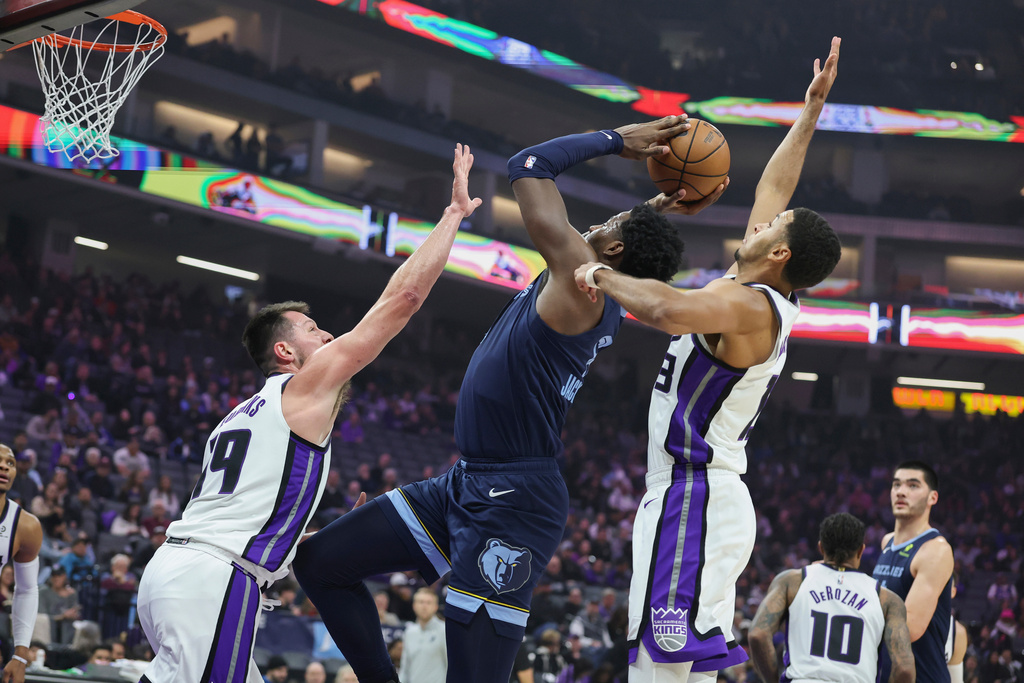 Memphis Grizzlies forward Jaren Jackson Jr., center, attempts to go up for a shot with Sacramento Kings center Drew Eubanks, left, and forward Keegan Murray, right, defending during the first half of an NBA basketball game Sunday, Nov. 30, 2025, in Sacramento, Calif. (AP Photo/Sara Nevis)