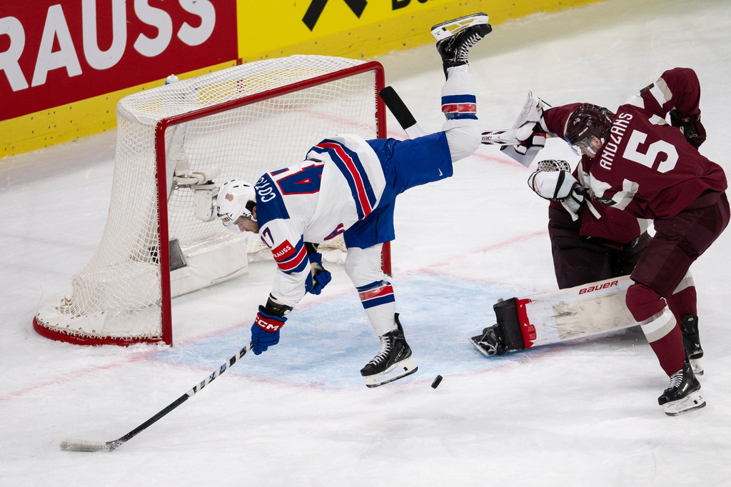 From left, USA's Paul Cotter, Latvia's goaltender Kristers Gudlevskis and Latvia's Arturs Andzans challenge for the puck during the 2026 IIHF Men's Ice Hockey World Championship preliminary round group A match between Latvia and the United States in Zurich, Switzerland, Saturday, May 23, 2026. (Andreas Becker/Keystone via AP)