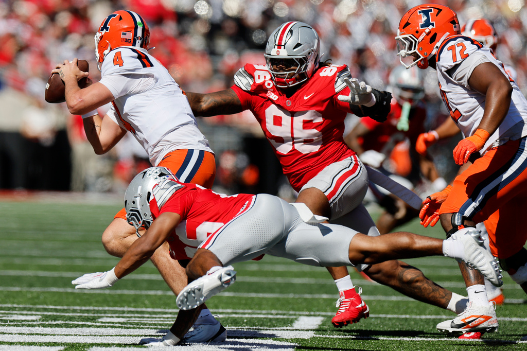 Illinois quarterback Katin Houser, left, scrambles away from Ohio State defensive back Jay Timmons, front, and defensive lineman Eddrick Houston during the second half of an NCAA college football game, Saturday, Sept. 26, 2026, in Columbus, Ohio. (AP Photo/Jay LaPrete)
