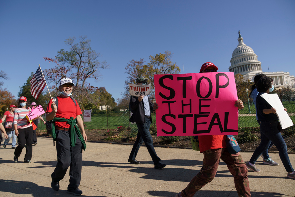 FILE - Supporters of President Donald Trump carry flags and signs as they parade past the Capitol in Washington, after news that President-elect Joe Biden had defeated the incumbent in the race for the White House, in Washington, Nov. 7, 2020. (AP Photo/J. Scott Applewhite, File)