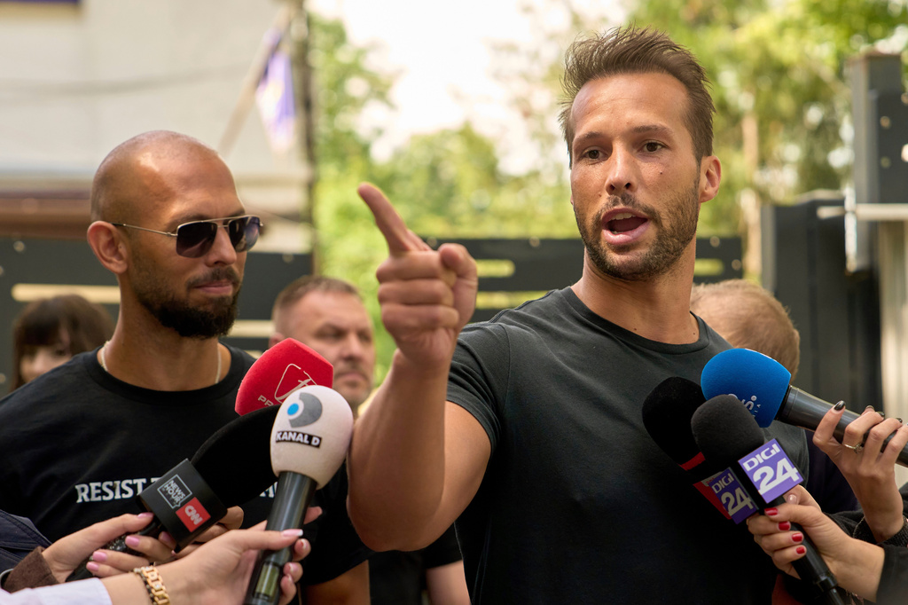 FILE - Andrew Tate, left, watches his brother Tristan speak, outside a police station in Voluntari, Romania, May 21, 2025. (AP Photo/Vadim Ghirda, File)
