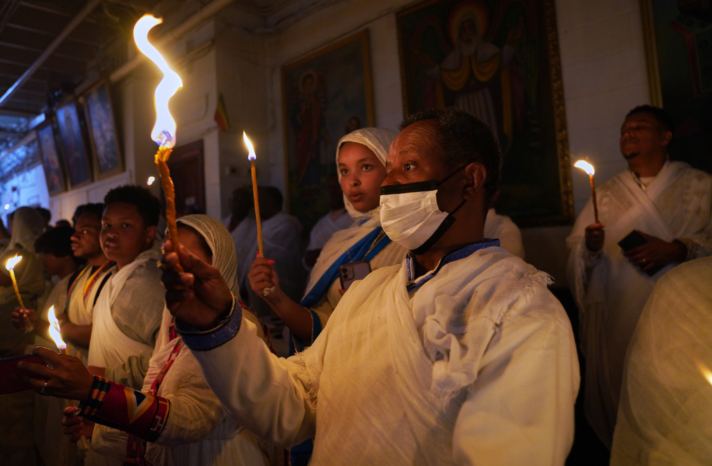 Congregants hold lit wax candles called tuaf during Easter service, to represent the moment of resurrection, when they believe the light of Christ dispelled the darkness at Re'ese Adbarat Debre Selam Kidist Mariam Church, an Ethiopian Orthodox Tewahedo church, in Washington, Saturday, April 11, 2026. (AP Photo/Jessie Wardarski)