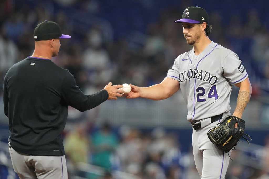 Colorado Rockies pitcher Michael Lorenzen (24) hand the bal to manager Warren Schaeffer, left, after being relieved during the fifth inning of a baseball game against the Miami Marlins, Saturday, March 28, 2026, in Miami. (AP Photo/Lynne Sladky)