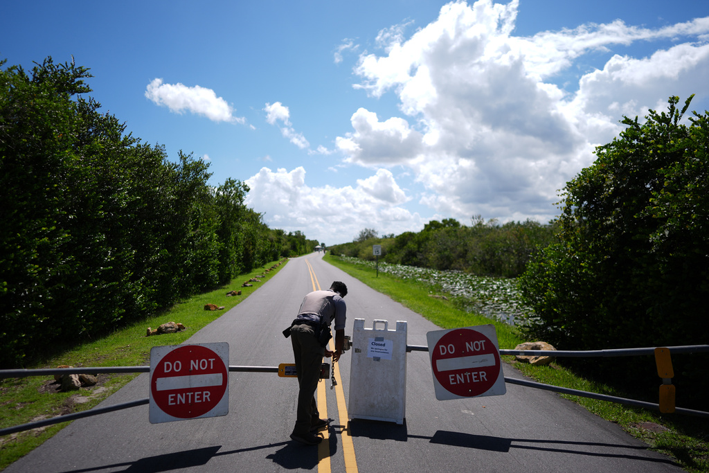 FILE - National Park Service law enforcement ranger Greg Freeman opens a locked gate closing vehicle access to the Shark Valley section of Florida's Everglades National Park, as he drives into the park, Oct. 1, 2025. (AP Photo/Rebecca Blackwell, File)