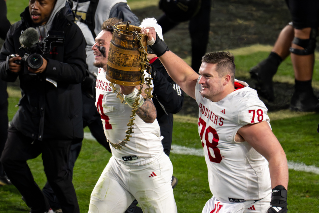 Indiana linebacker Aiden Fisher (4) and offensive lineman Pat Coogan (78) celebrate with the Old Oaken Bucket trophy after an NCAA college football game against Purdue, Friday, Nov. 28, 2025, in West Lafayette, Ind. (AP Photo/Doug McSchooler)