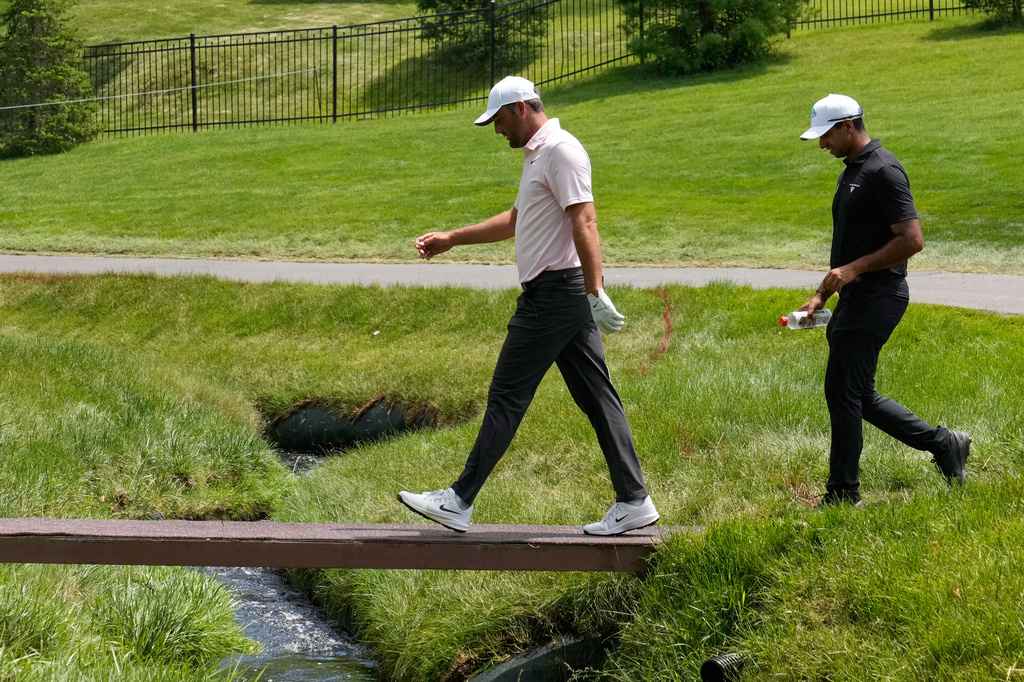 Scottie Scheffler, left, and Aaron Rai, of England, right, walk across a bridge on the second fairway during the first round of the Memorial golf tournament in Dublin, Ohio, Thursday, June 4, 2026. (AP Photo/Sue Ogrocki)