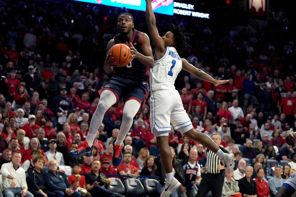 Arizona guard Jaden Bradley scores on BYU guard Robert Wright III (1) during the second half of an NCAA college basketball game, Wednesday, Feb. 18, 2026, in Tucson, Ariz. (AP Photo/Rick Scuteri)
