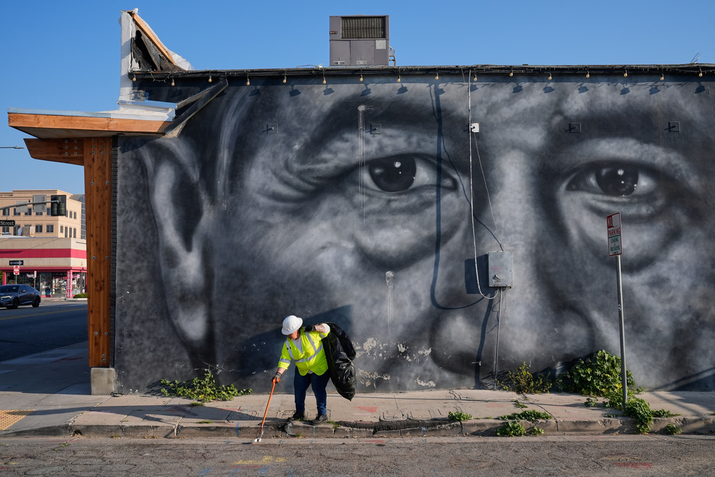 A sanitation worker picks up trash next to a mural of César Chavez in Bakersfield, Calif., Thursday, March 19, 2026. (AP Photo/Godofredo A. Vásquez)