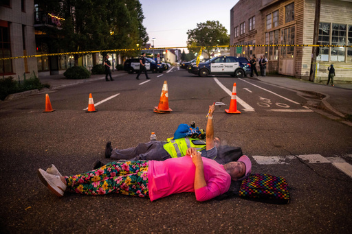 People relax on a street outside a U.S. Immigration and Customs Enforcement facility on Tuesday, Oct. 7, 2025, in Portland, Ore. (AP Photo/Ethan Swope) People relax on a street outside a U.S. Immigration and Customs Enforcement facility on Tuesday, Oct. 7, 2025, in Portland, Ore. (AP Photo/Ethan Swope)