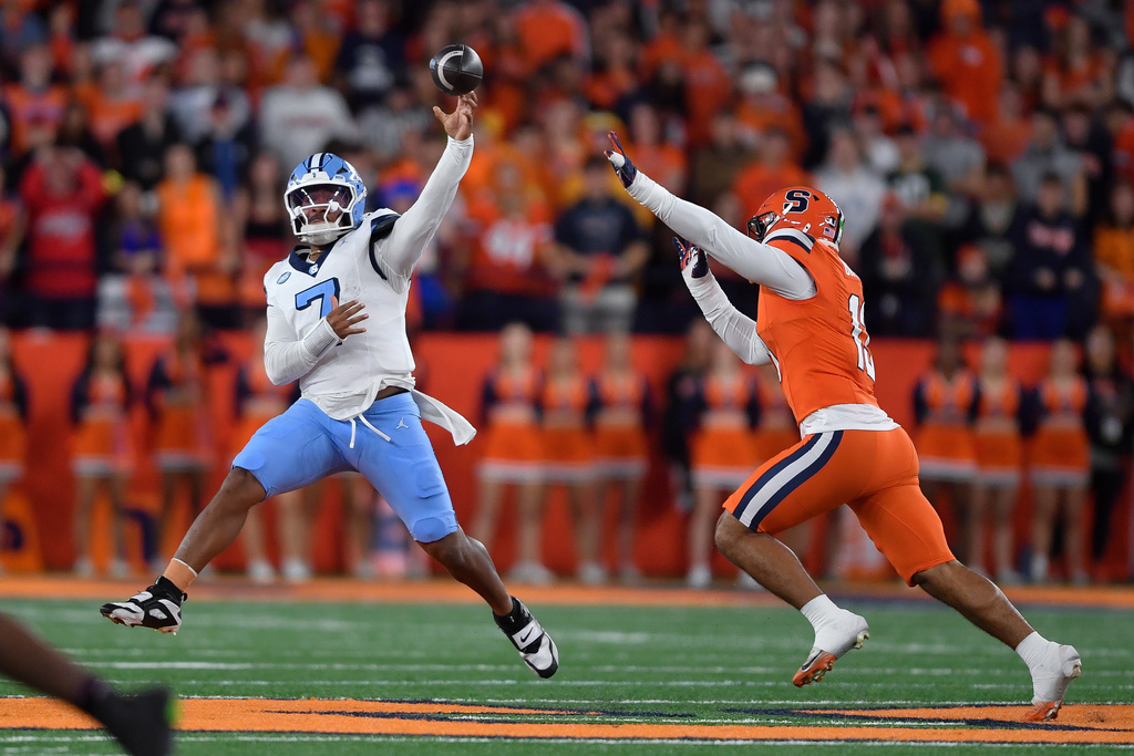 North Carolina quarterback Gio Lopez, left, throws while pressured by Syracuse linebacker Gary Bryant III, right, during the first half of an NCAA college football game Friday, Oct. 31, 2025, in Syracuse, N.Y. (AP Photo/Adrian Kraus)