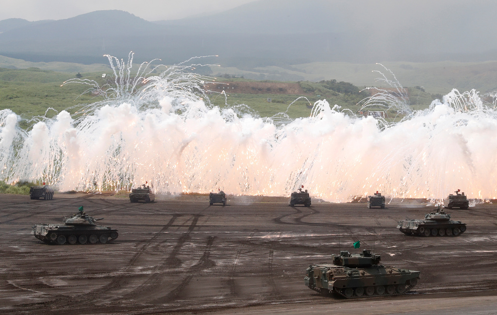 FILE - Japan Ground Self-Defense Force's tanks flare up a smoke screen during an annual live firing exercise at Higashi Fuji range in Gotemba, southwest of Tokyo on Aug. 24, 2017. (AP Photo/Eugene Hoshiko, File)