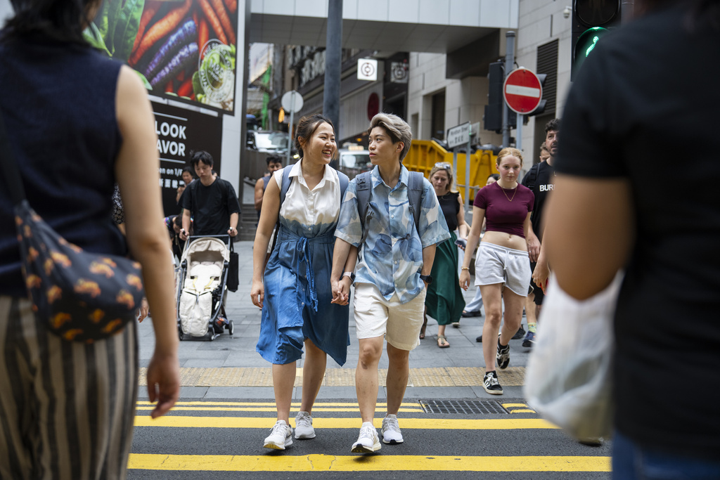 Same-sex partners Jaedyn Yu, right and Gloria Tsang cross the road in Hong Kong, Sunday, Aug. 24, 2025. (AP Photo/Chan Long Hei)