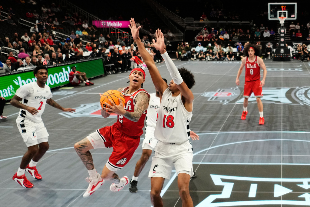 Utah guard Terrence Brown (2) shoots under pressure from Cincinnati forward Baba Miller (18) during the first half of an NCAA college basketball game at the Big 12 Conference tournament Tuesday, March 10, 2026, in Kansas City, Mo. (AP Photo/Charlie Riedel)