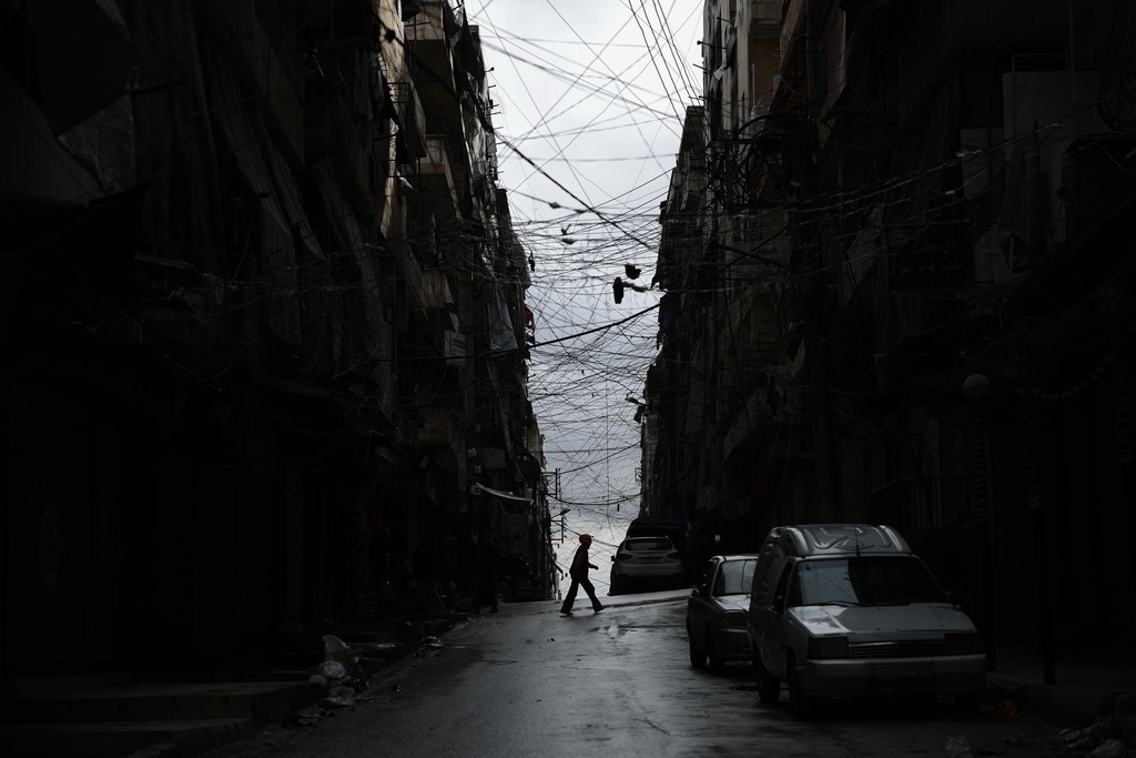 A man crosses a street in the predominantly Kurdish Sheikh Maqsoud neighborhood after days of fighting between government forces and Kurdish fighters in the northern city of Aleppo, Syria, Tuesday, Jan. 13, 2026. (AP Photo/Ghaith Alsayed)