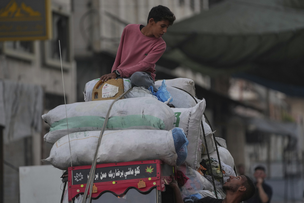 Displaced Palestinians fleeing Jabaliya move with their belongings on a street in Gaza City, Tuesday, Aug. 26, 2025. (AP Photo/Jehad Alshrafi)