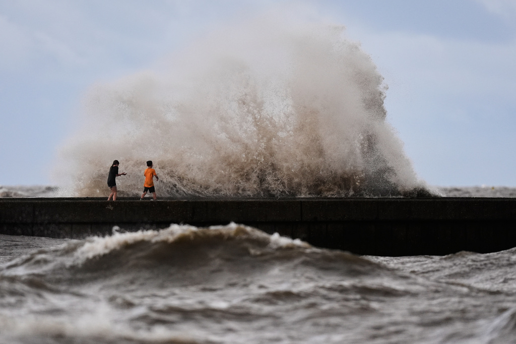 Children play near breaking waves on West End Pier on Lake Pontchartrain as Tropical Storm Bertha approaches the Louisiana Coast Wednesday, July 22, 2026, in New Orleans. (AP Photo/Gerald Herbert)