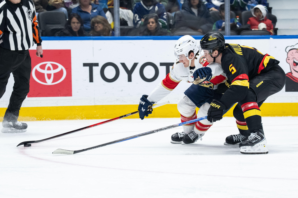 Florida Panthers' Mackie Samoskevich and Vancouver Canucks' Tom Willander (5) vie for the puck during the second period of an NHL hockey game in Vancouver, Tuesday, March 17, 2026. (Ethan Cairns/The Canadian Press via AP)