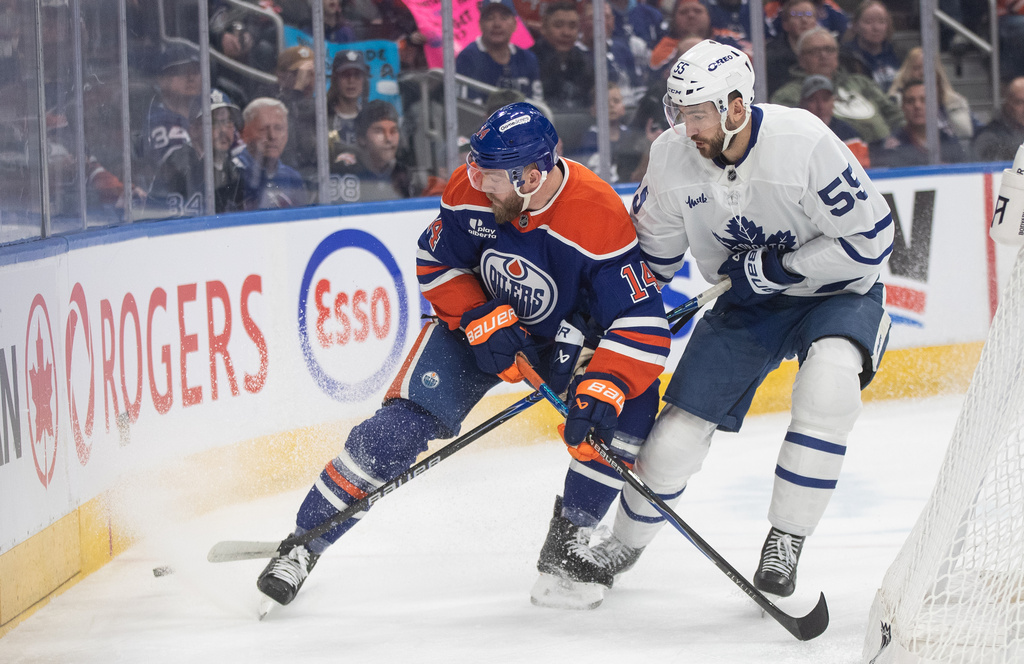 Toronto Maple Leafs' Nicolas Roy (55) and Edmonton Oilers' Mattias Ekholm (14) battle for the puck during first period NHL action, in Edmonton on Tuesday, Feb. 3, 2026. (Jason Franson/The Canadian Press via AP)