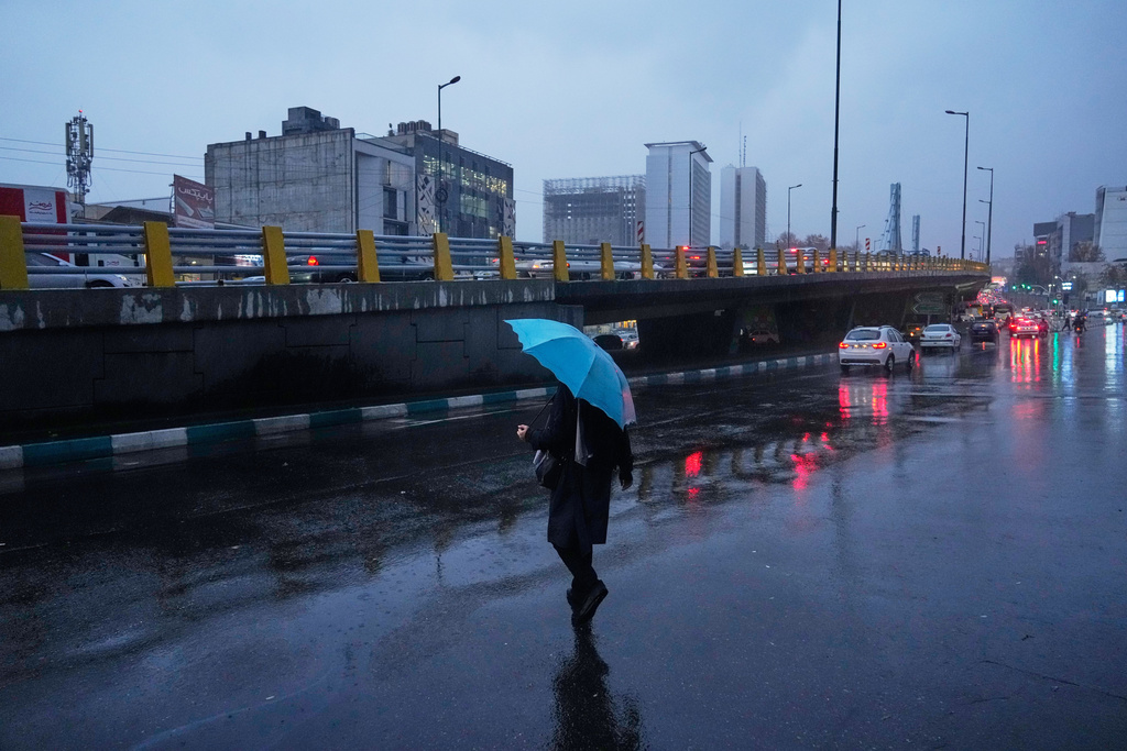 A woman holds an umbrella while crossing a street as rain falls in Tehran, Iran, Wednesday, Dec. 10, 2025. (AP Photo/Vahid Salemi)