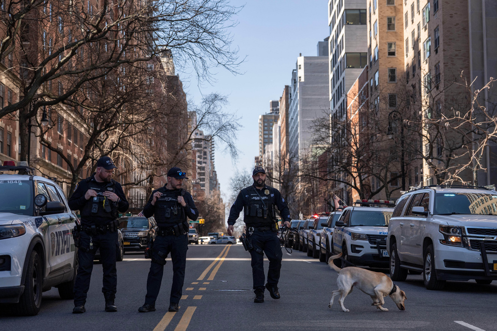 NYPD police officer and K-9 dog walks outside Carl Schurz Park as they investigate suspicious device, Tuesday, March 10, 2026, in New York. (AP Photo/Yuki Iwamura)