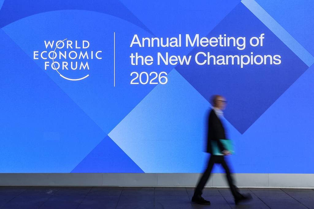 In this photo released by Xinhua News Agency, a participant passes by a billboard promoting the Annual Meeting of the New Champions in Dalian, northeastern China's Liaoning Province, on Tuesday, June 23, 2026. (Pan Yulong/Xinhua via AP)