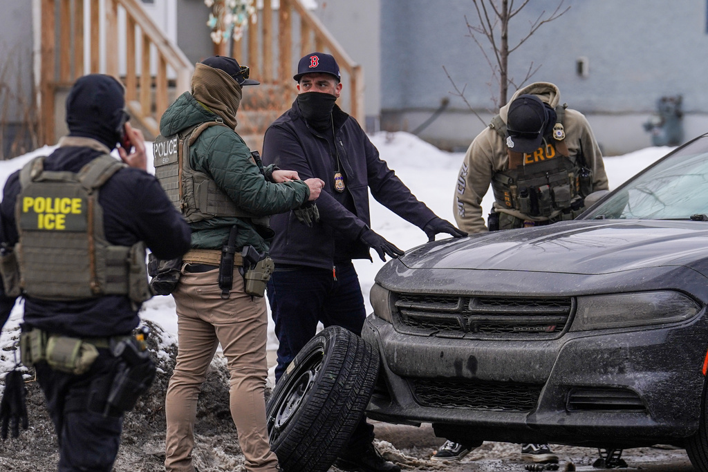 Federal agents tend to a vehicle with a flat tire while conducting immigration enforcement operations, Thursday, Feb. 5, 2026, in Minneapolis. (AP Photo/Ryan Murphy)