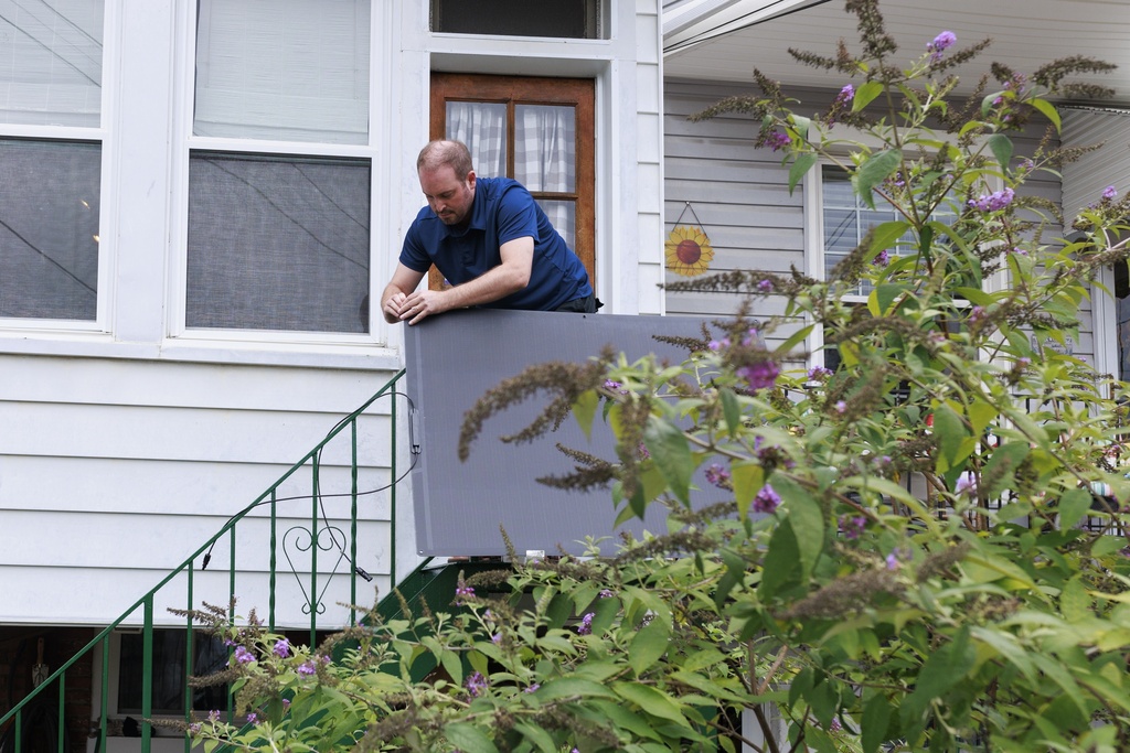 Craig Keenan installs a solar panel from Bright Saver on Friday, Aug. 1, 2025, in Baltimore. (AP Photo/KT Kanazawich)