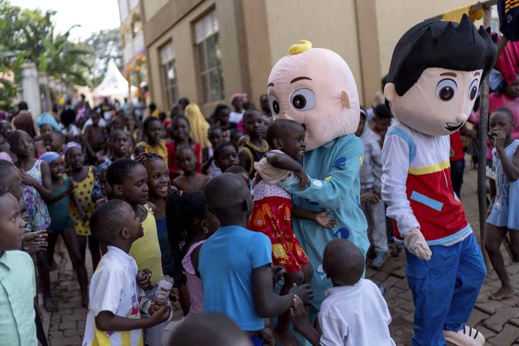 Children gather around people dressed as characters from a popular children's television show during a school's kindergarten graduation party, Saturday, Nov. 23, 2024, in Kampala, Uganda. (AP Photo/David Goldman)