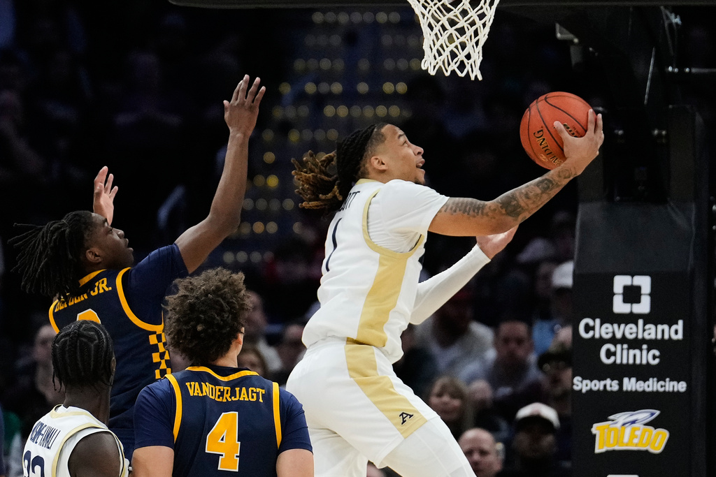 Akron guard Shammah Scott, right, goes to the basket in front of Toledo guard Leroy Blyden Jr., left, in the first half of an NCAA college basketball game in the championship of the Mid-American Conference tournament, Saturday, March 14, 2026, in Cleveland. (AP Photo/Sue Ogrocki)