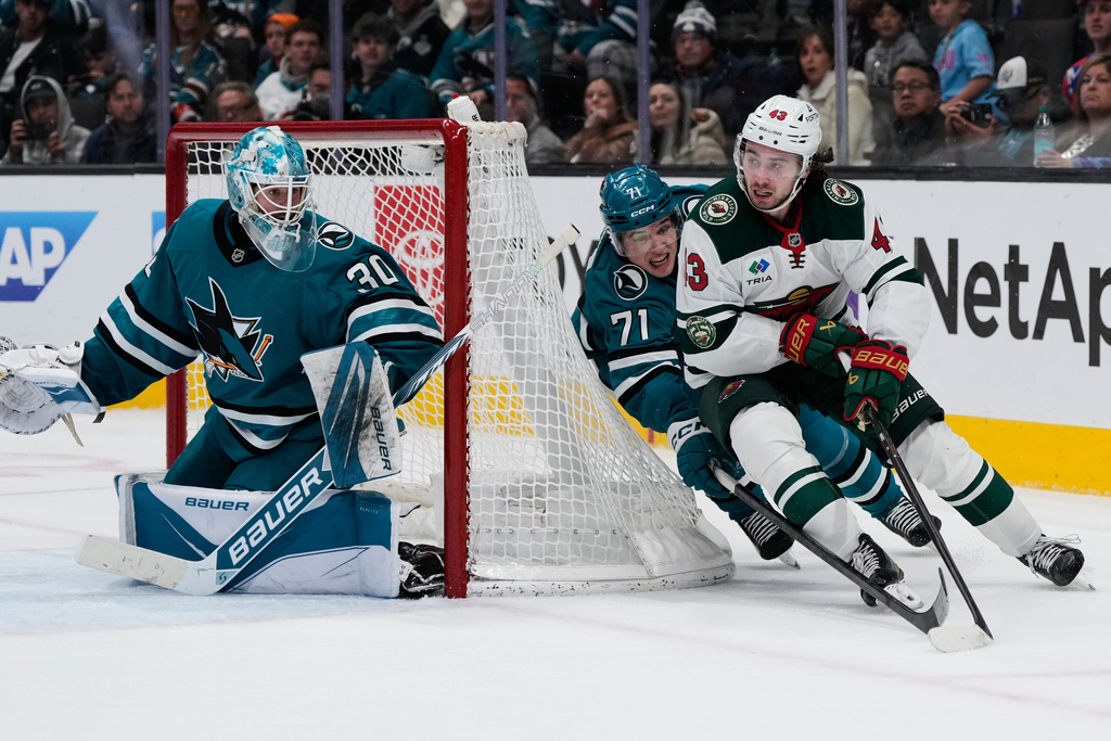 Minnesota Wild defenseman Quinn Hughes (43) moves the puck while defended by San Jose Sharks center Macklin Celebrini (71) during overtime of an NHL hockey game, Wednesday, Dec. 31, 2025, in San Jose, Calif. (AP Photo/Godofredo A. Vásquez)