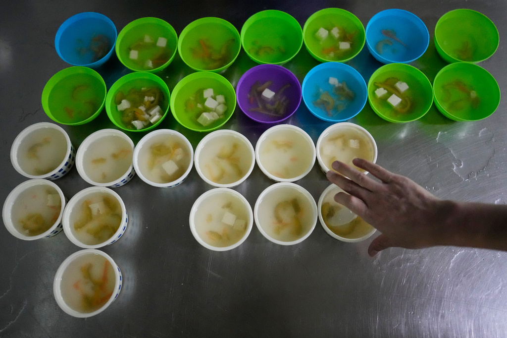 A rescued scam worker picks out soup at the canteen at the Presidential Anti-Organized Crime Commission temporary detention center, a former scam compound in Pasay, Philippines, Tuesday, June 3, 2025. (AP Photo/Aaron Favila)