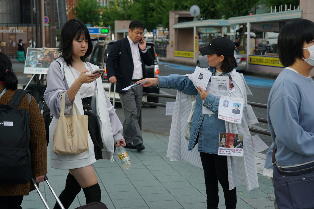 Yang Caiying, who is living in exile in Japan, shows a leaflet protesting Chinese state repression of her family to pedestrians in Nagoya, Japan, Friday, May 17, 2024. (AP Photo/Dake Kang)