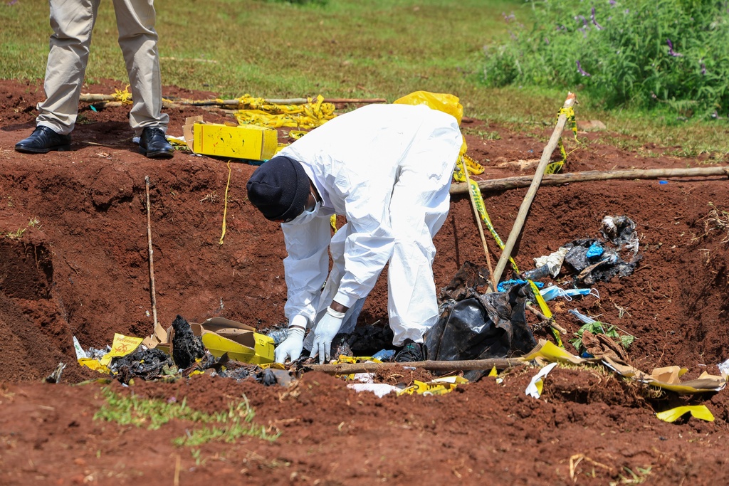 Directorate of Criminal Investigations (DCI) forensic staff inspect the scene of a mass grave where 33 bodies were exhumed at a cemetery in Kericho, Western Kenya Thursday, March 26, 2026. (AP Photo/Andrew Kasuku)