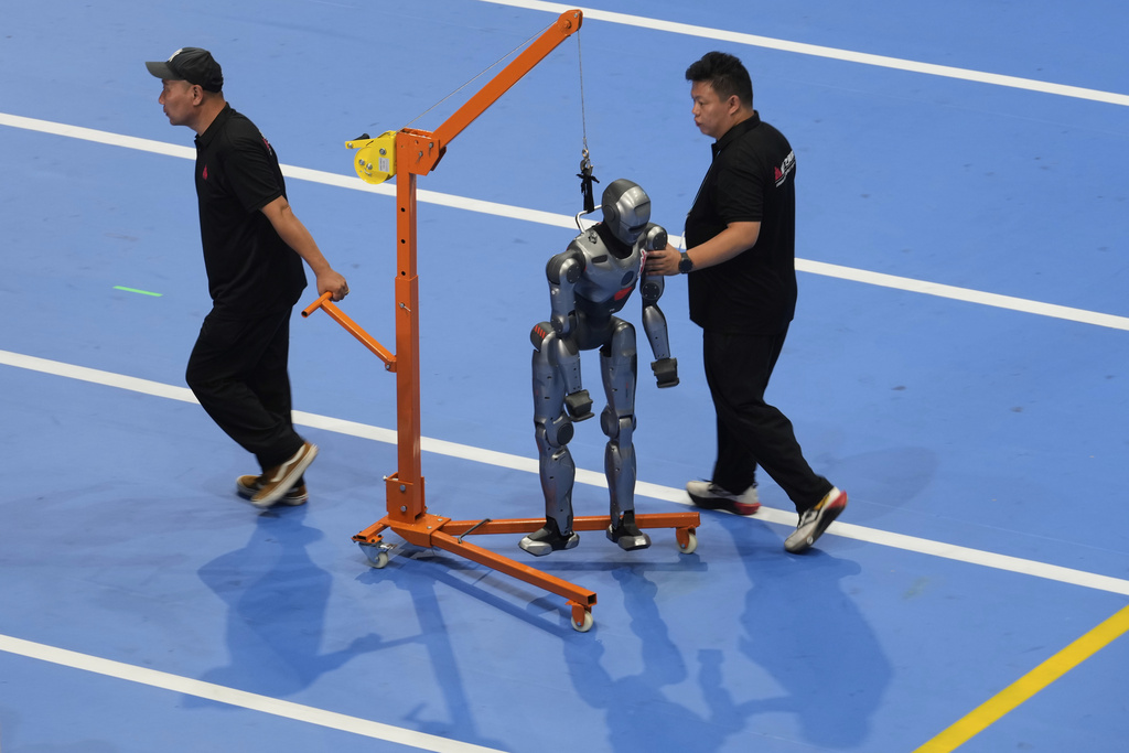 Workers transfer a robot before the opening ceremony for the World Humanoid Robot Games held in Beijing, China, Thursday, Aug. 14, 2025. (AP Photo/Mahesh Kumar A.)