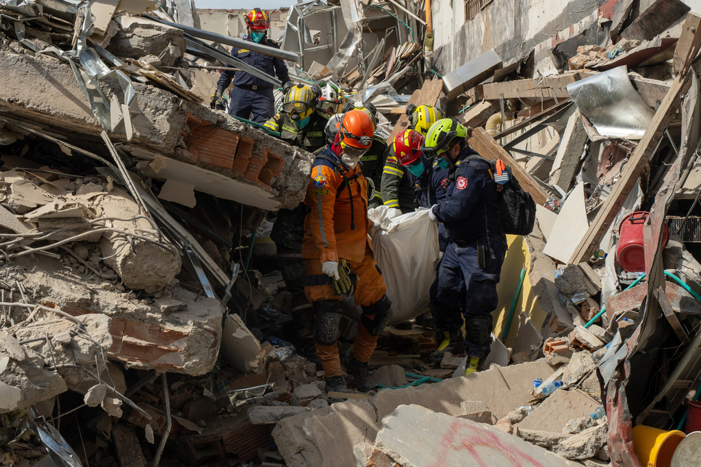 Rescuers carry the body of a victim from the rubble four days after an earthquake hit Pereira, Colombia, Friday, Aug. 14, 2026. (AP Photo/Brandon Pinto)