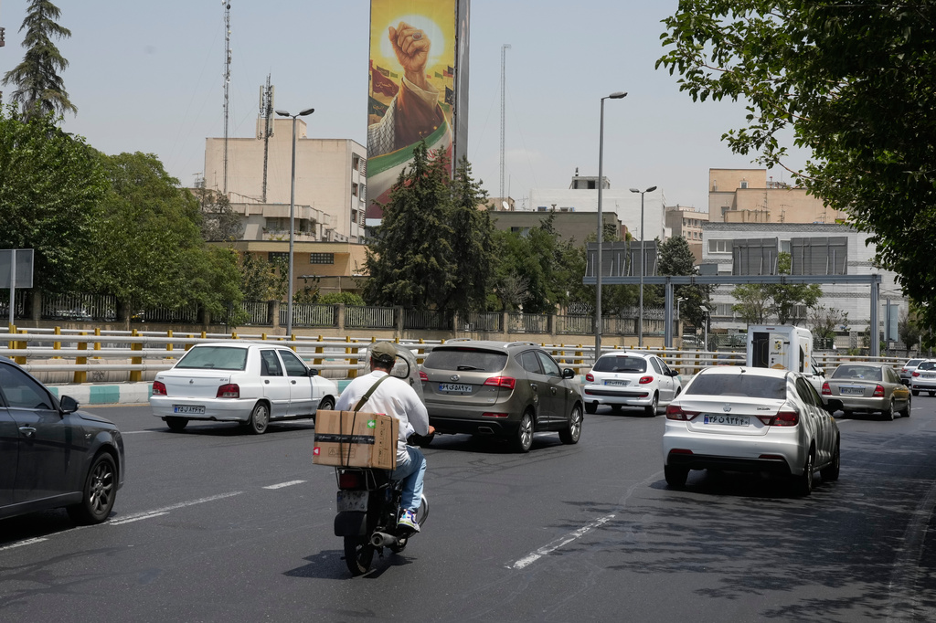 Vehicles drive past a billboard depicting the clenched fist of the late Iranian Supreme Leader Ayatollah Ali Khamenei, in Tehran, Iran, Tuesday, July 21, 2026. (AP Photo/Vahid Salemi)