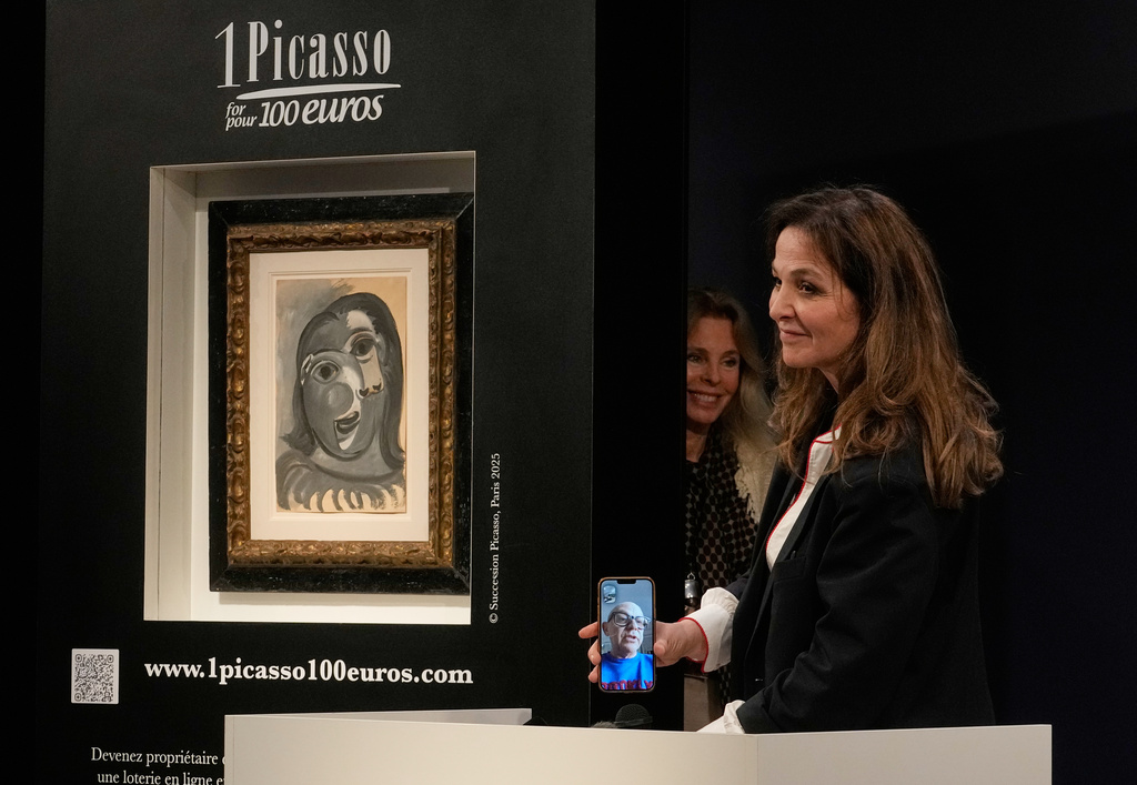 Peri Cochin, right, founder of "1 Picasso for 100 euros," speaks on the phone with the winner, Ari Hodara of Paris, next to the painting 'Head of a Woman' by Pablo Picasso, painted in 1941, after the raffle draw at Christie's in Paris, Tuesday, April 14, 2026, in support of Alzheimer's research. (AP Photo/Michel Euler)