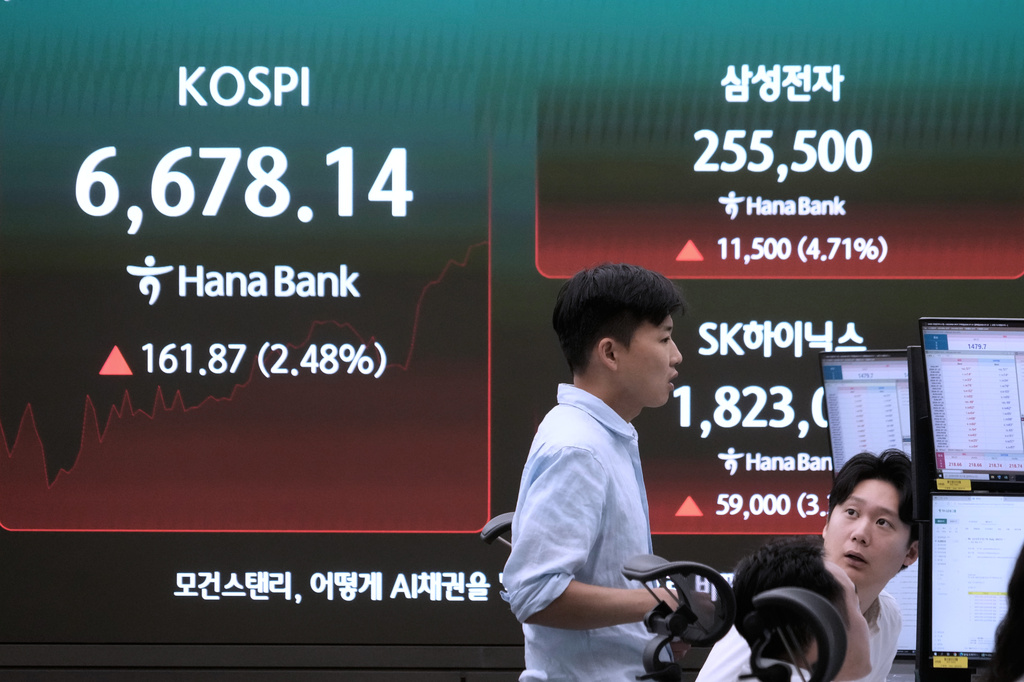 Currency traders work near a screen showing the Korea Composite Stock Price Index (KOSPI), SK Hynix and Samsung Electronics Co. stock price at the foreign exchange dealing room of the Hana Bank headquarters in Seoul, South Korea, Tuesday, July 21, 2026. (AP Photo/Ahn Young-joon)