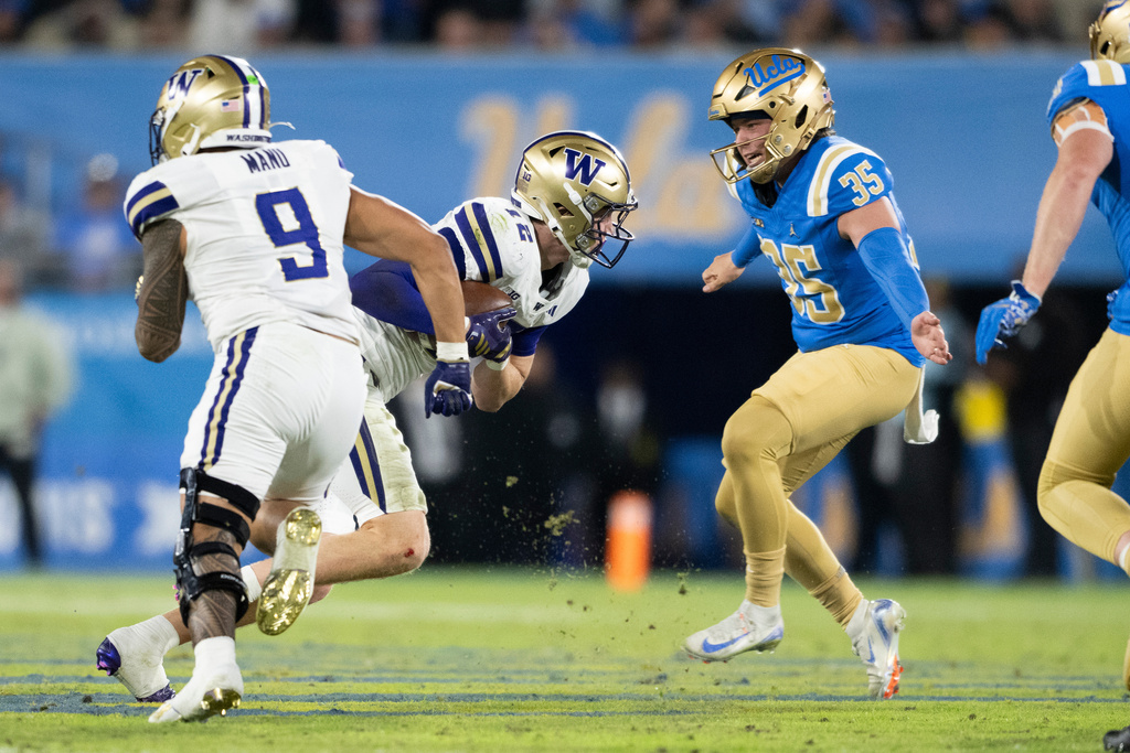 Washington safety Alex McLaughlin recovers a fumble as UCLA kicker Cash Peterman defends during the first half of an NCAA college football game, Saturday, Nov. 22, 2025, in Pasadena, Calif. (AP Photo/Kyusung Gong)