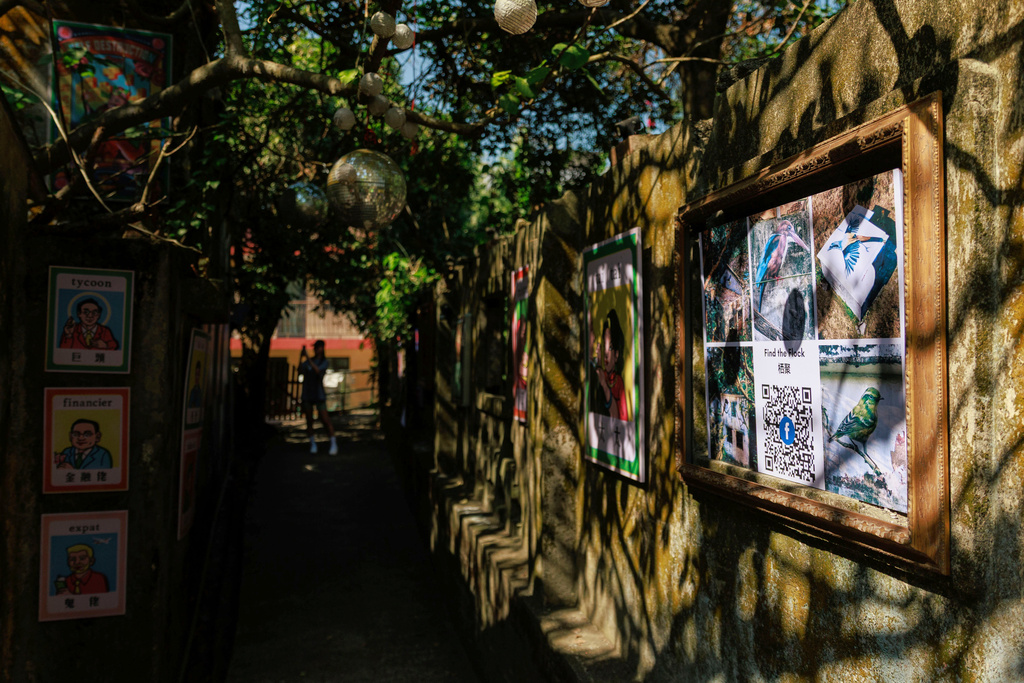 A person takes photo of art works at Wang Tong Art Walk, where the first bird mural from the Flock Project begins, in Lantau, Hong Kong, Nov. 16, 2025. (AP Photo/May James)