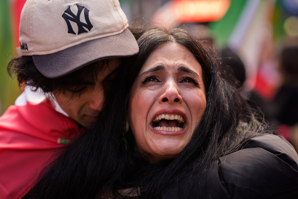 Noora cries as she is embraced by Pi, both Iranian, while singing a rendition of Iranian patriotic song Ey Iran, during a rally in reaction to U.S. and Israeli strikes on Iran, Sunday, March 1, 2026 in New York. (AP Photo/Adam Gray)