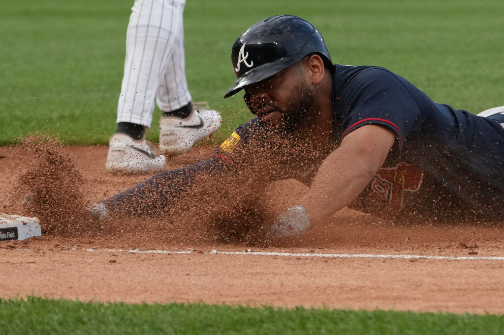Atlanta Braves' Dominic Smith dives into first base safely against the Chicago White Sox during the third inning in a baseball game Wednesday, June 10, 2026, in Chicago. (AP Photo/David Banks)