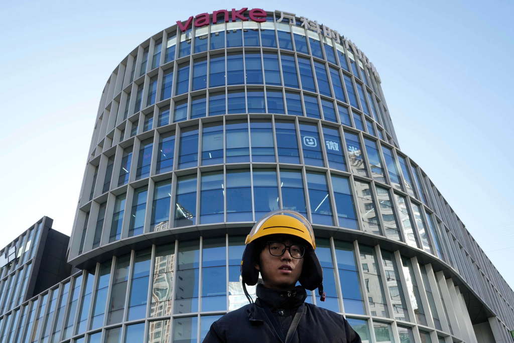A delivery man passes by a Vanke logo on a commercial complex in Beijing, China, Wednesday, Dec. 24, 2025. (AP Photo/Ng Han Guan)