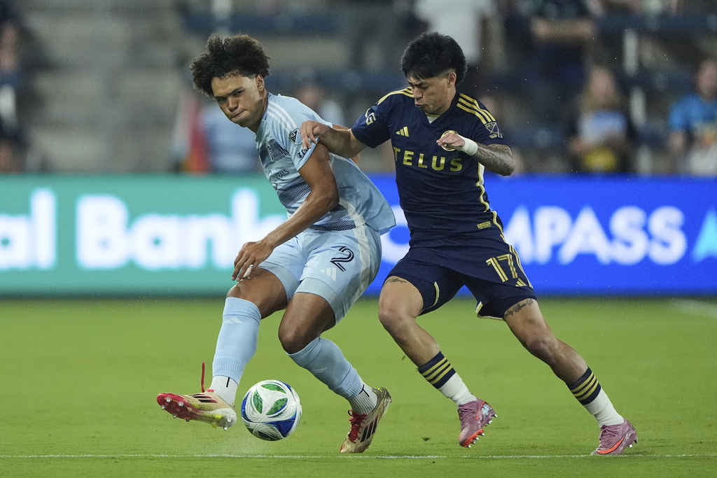 Sporting Kansas City defender Ian James (2) and Vancouver Whitecaps midfielder Kenji Cabrera (17) chase after the ball during the first half of an MLS soccer match Saturday, Sept. 20, 2025, in Kansas City, Kan. (AP Photo/Charlie Riedel)