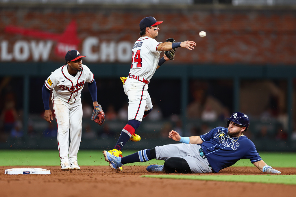 Atlanta Braves shortstop Mauricio Dubón, center, throws to first base while Tampa Bay Rays' Jonathan Aranda, right, slides in the third inning of a baseball game, Tuesday, Sept. 8, 2026, in Atlanta. (AP Photo/Colin Hubbard)