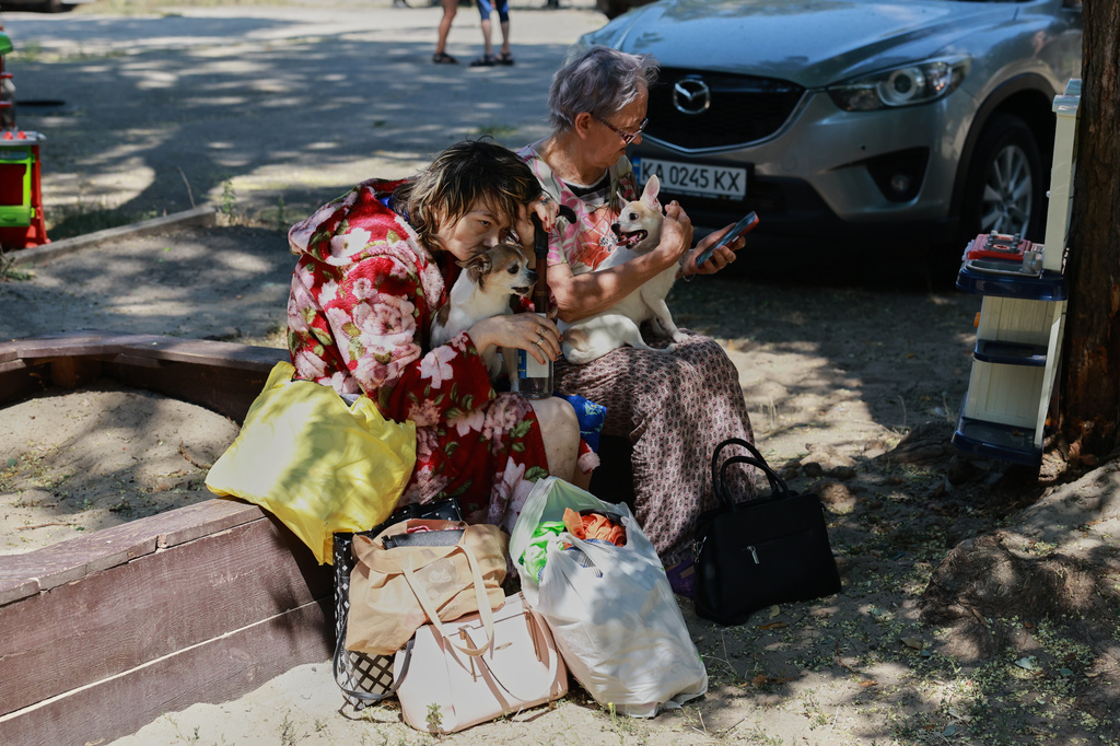 Local residents sit with their dogs after a Russian air guided bomb strike damaged their home in Zaporizhzhia, Ukraine, Monday, Aug. 10, 2026. (AP Photo/Kateryna Klochko)