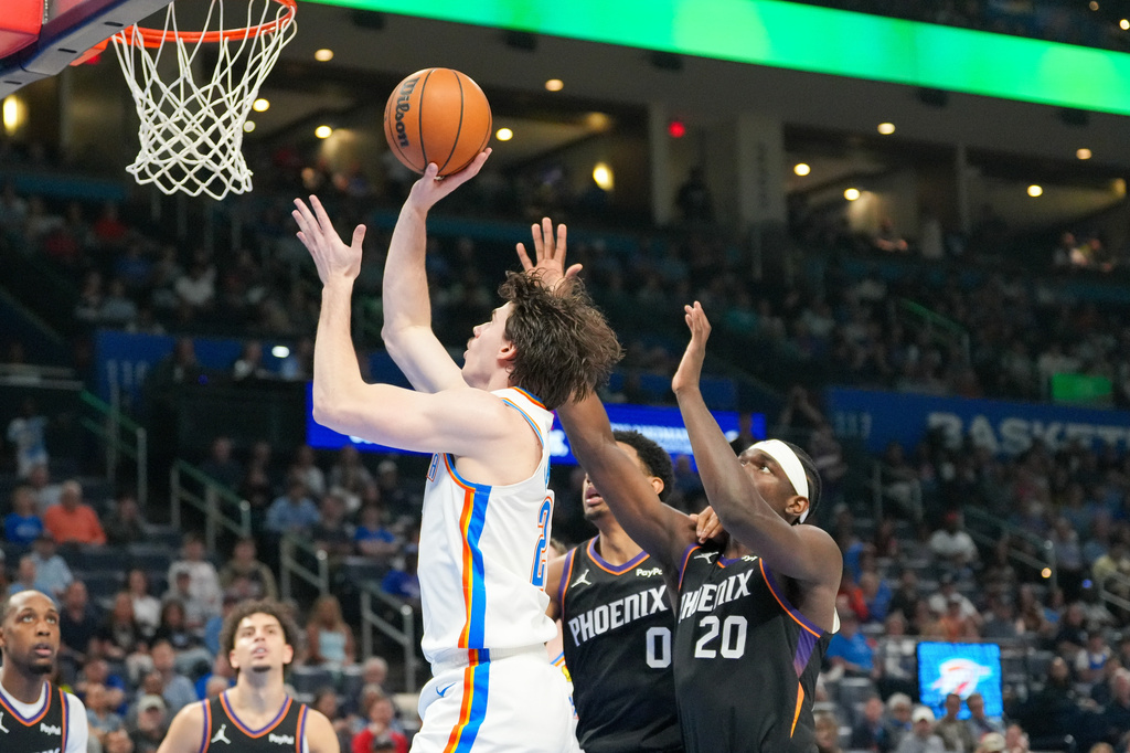 Oklahoma City Thunder forward Brooks Barnhizer, left, shoots in front of Phoenix Suns forwards Ryan Dunn, middle and Rasheer Fleming, right, during the second half of an NBA basketball game, Sunday, April 12, 2026, in Oklahoma City. (AP Photo/Kyle Phillips)