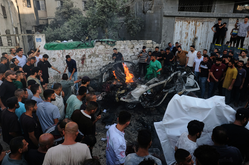 Palestinians gather around a car struck in an Israeli military strike in Gaza City, Sunday, Aug. 2, 2026. (AP Photo/Jehad Alshrafi)