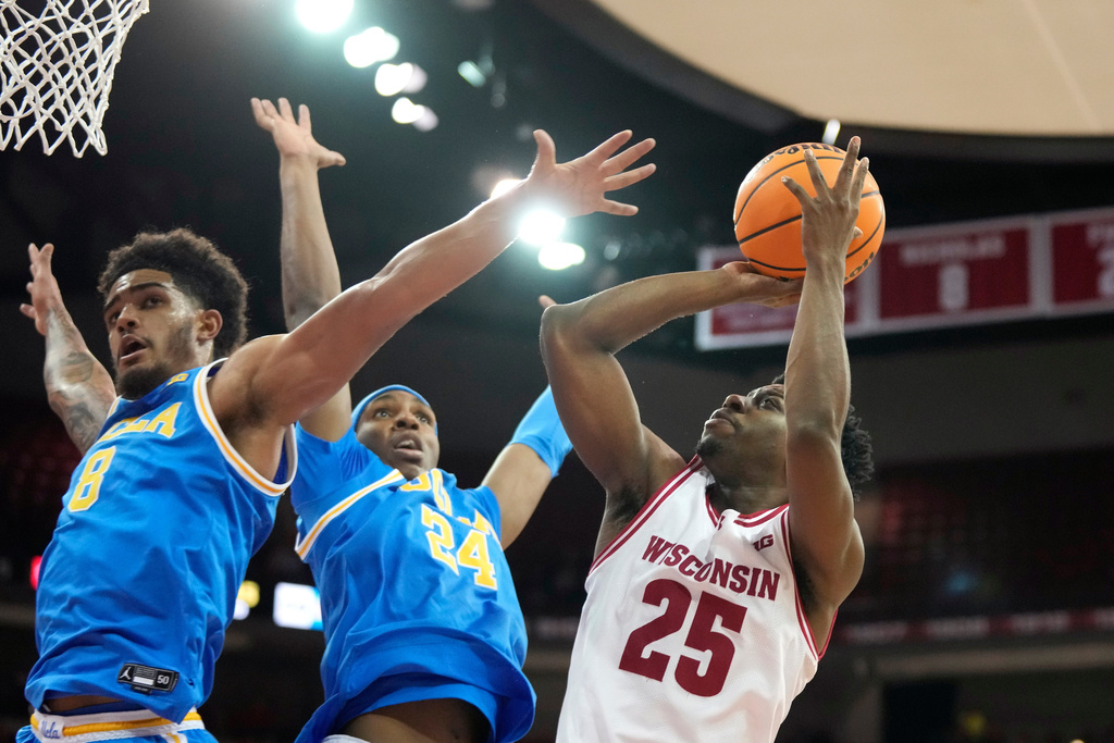 Wisconsin guard John Blackwell (25) scores against UCLA guard Eric Freeny (8) and UCLA center Steven Jamerson II (24) during the second half of an NCAA college basketball game Tuesday, Jan. 6, 2026, in Madison, Wis. (AP Photo/Kayla Wolf)